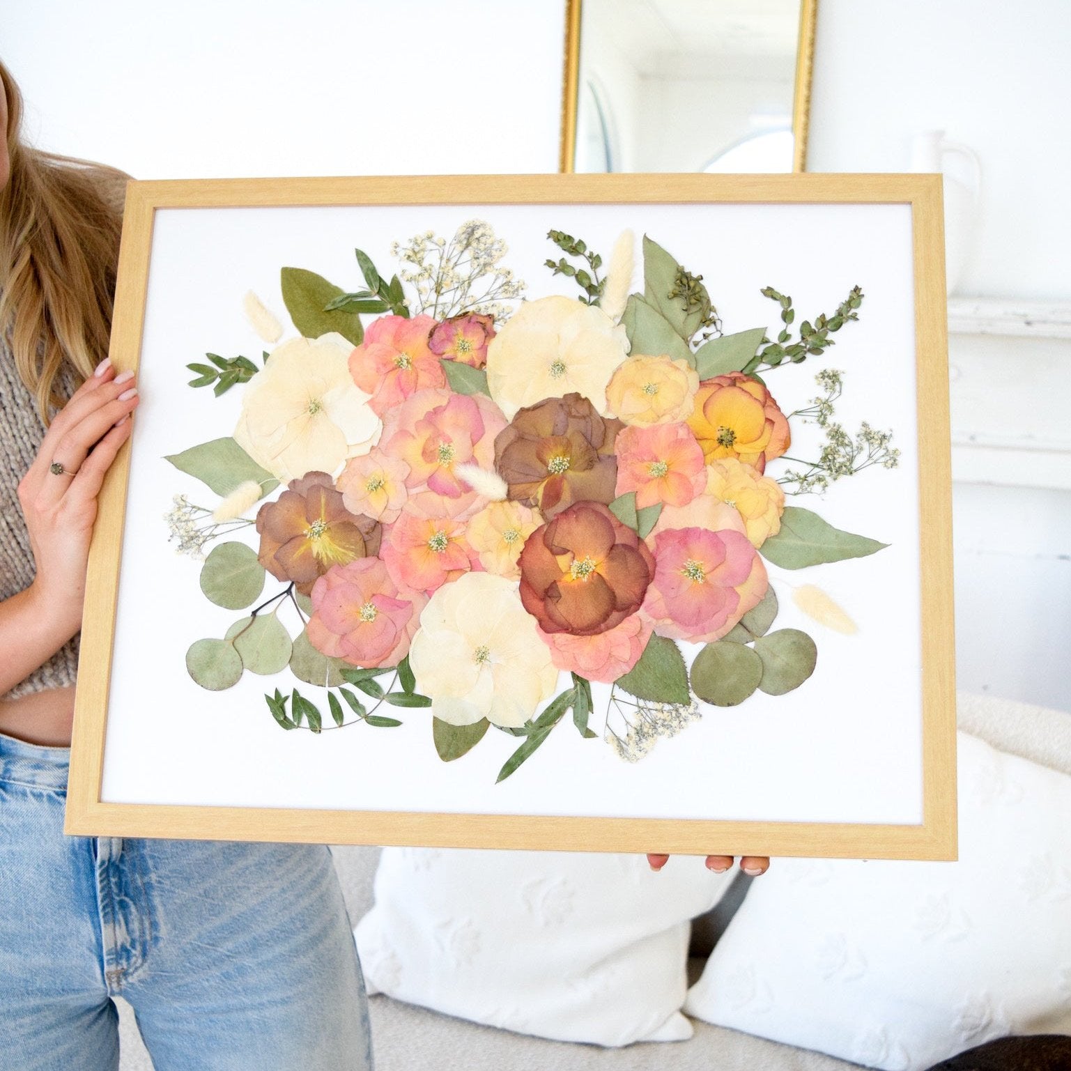 Preserved flowers pressed into simple wooden frame with white background.