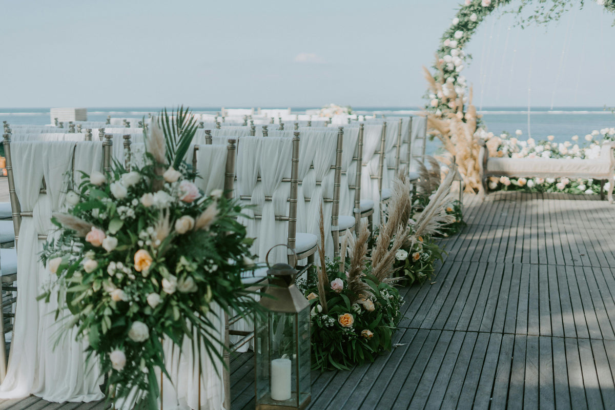 Beach wedding bouquet with white orchids and roses during an oceanfront ceremony at sunset, featuring coastal floral design and natural seaside scenery.
