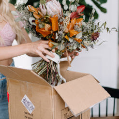 Bride carefully packing her wedding bouquet in a shipping box for professional flower preservation with Blossom & Rhyme