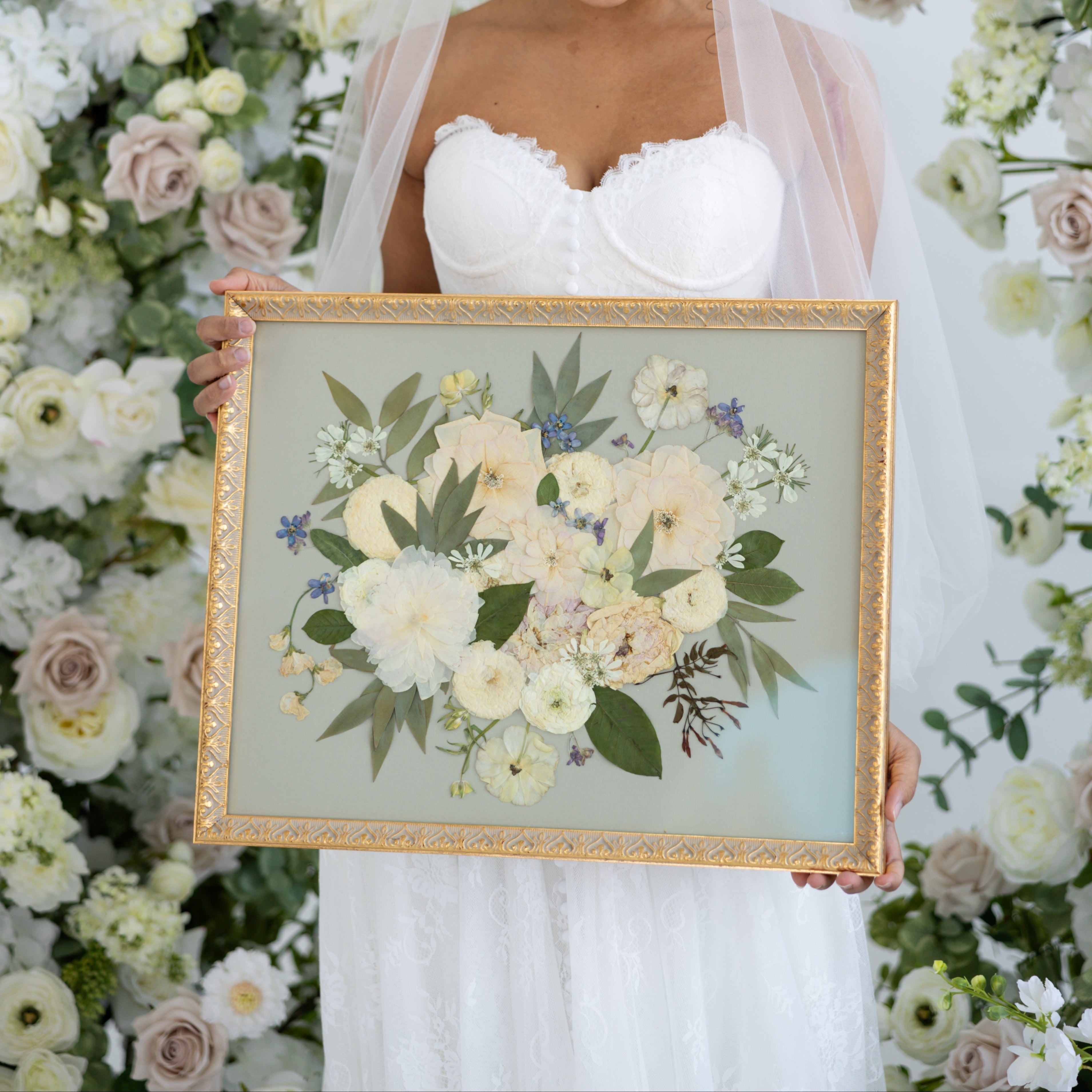 Bride holding a winter bouquet of white roses, ranunculus, evergreen foliage, and berries after the ceremony.