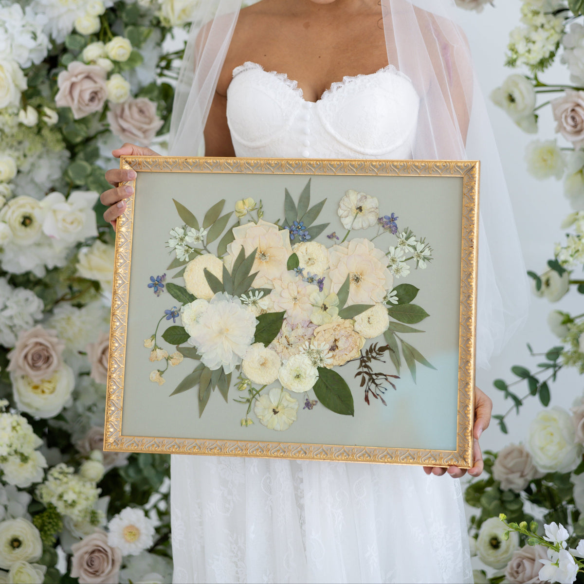 Bride holding a winter bouquet of white roses, ranunculus, evergreen foliage, and berries after the ceremony.