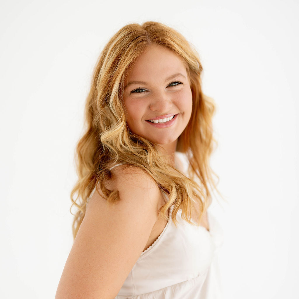 Blossom & Rhyme team member wearing a white sleeveless top on a white background.