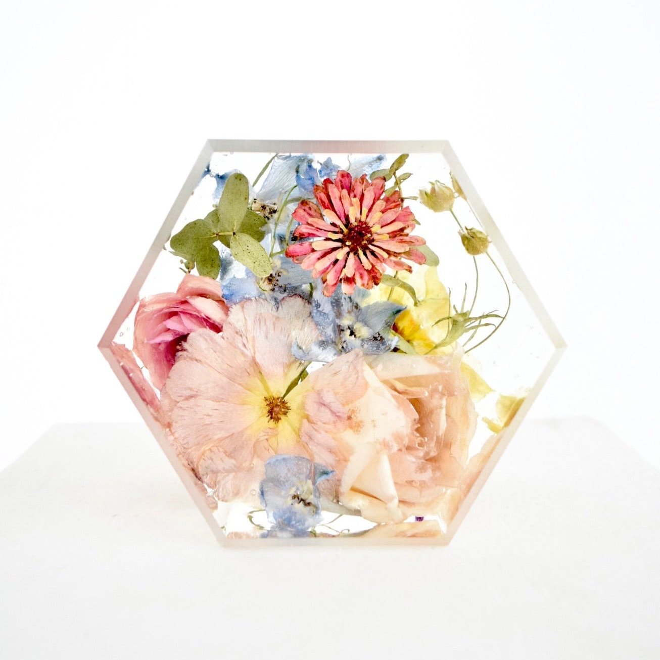 A hexagon-shaped preserve with an assortment of dried flowers in shades of pink, blue, and yellow.