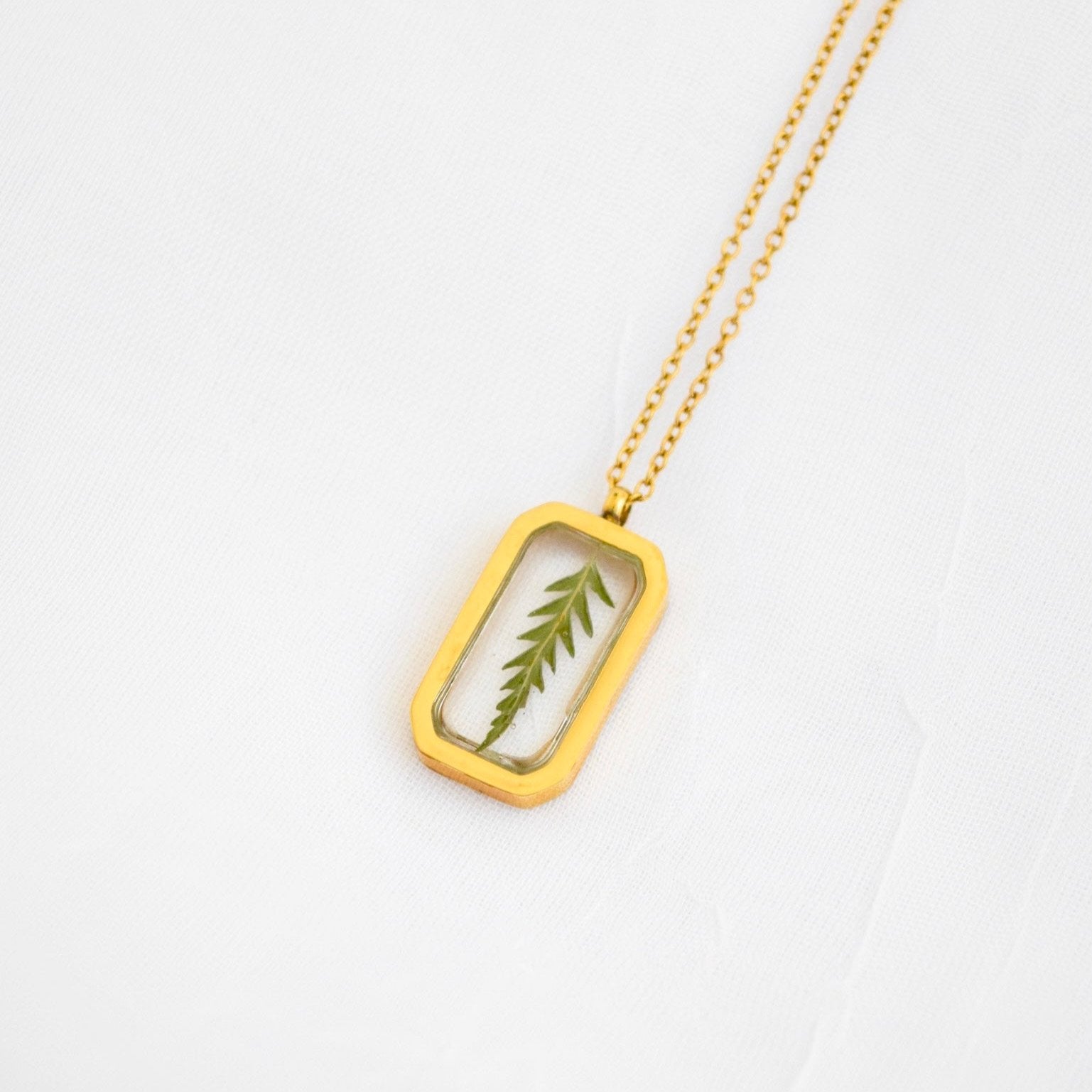 Gold necklace pendant featuring a preserved botanical keepsake handcrafted by Blossom & Rhyme