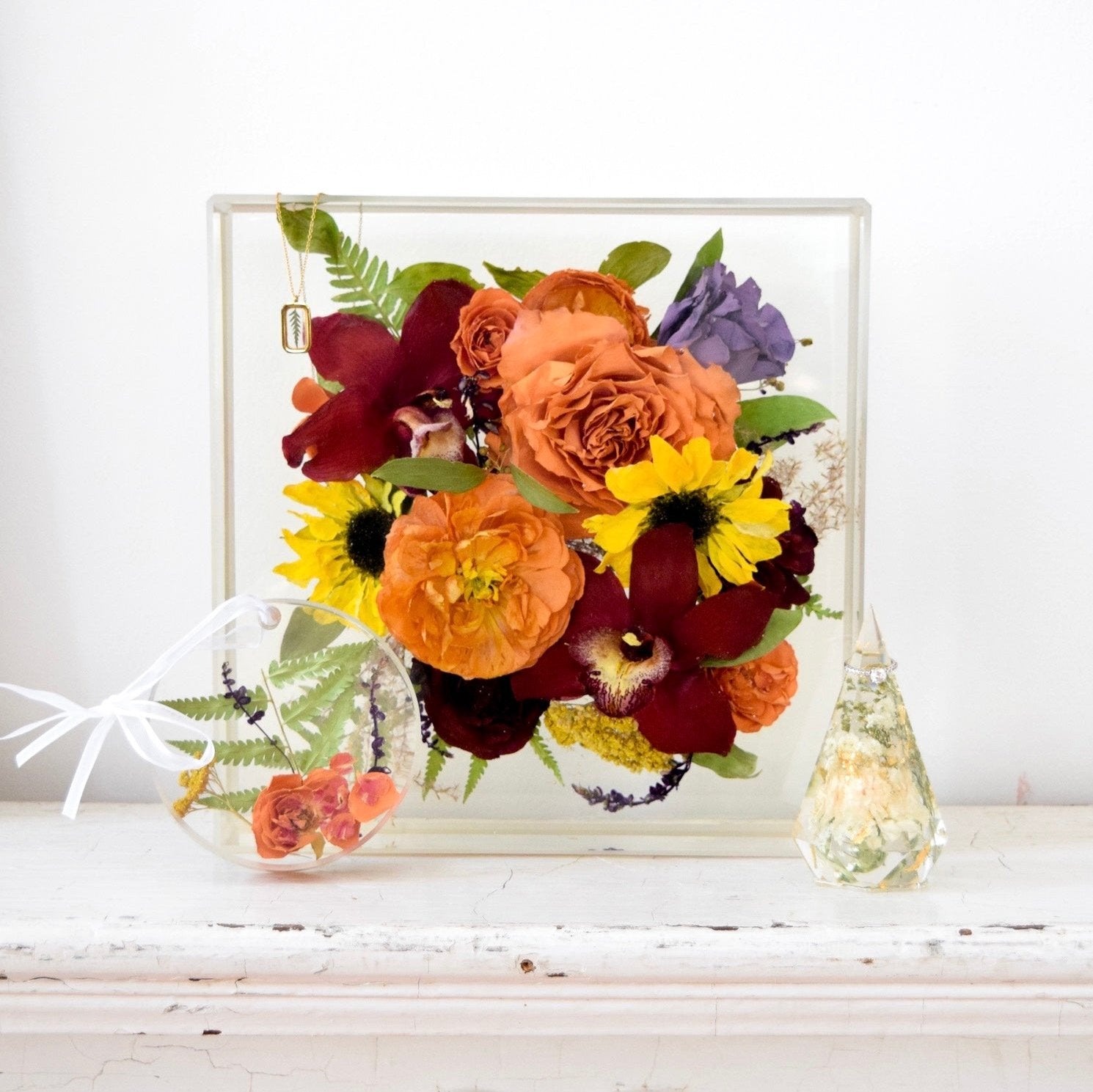 Resin floral keepsake collection featuring a large resin floral block, custom floral ornament, and faceted floral keepsake preserving orange garden roses, burgundy orchids, yellow sunflowers, purple hydrangeas, ranunculus, fern fronds, and botanical greenery, handcrafted by Blossom & Rhyme