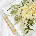Close-up of a resin floral tray preserving ivory roses, white hydrangeas, ranunculus, stock flowers, eucalyptus, olive leaves, and delicate greenery in clear resin, handcrafted by Blossom & Rhyme