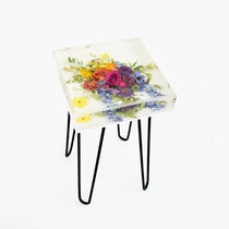 A square side table with a resin top featuring a floral design and a depth of up to 4 inches, supported by metal hairpin legs.