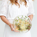 Woman holding a custom round resin floral keepsake crafted with preserved wedding flowers.
