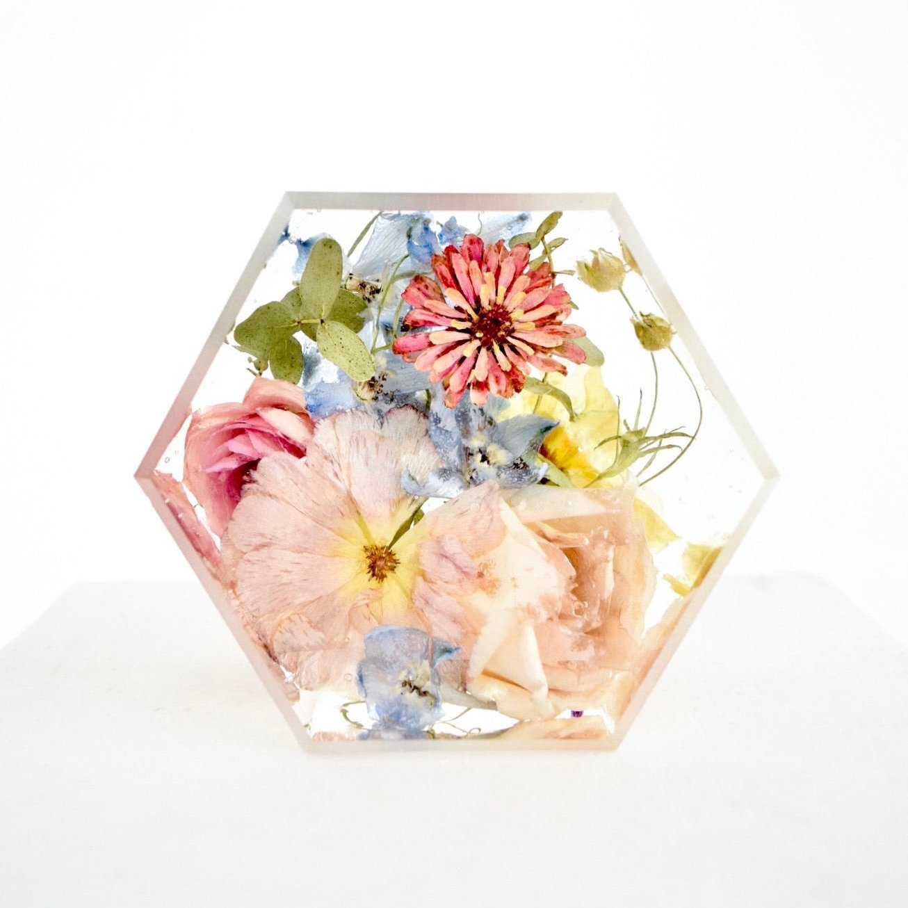 A hexagon-shaped preserve with an assortment of dried flowers in shades of pink, blue, and yellow.