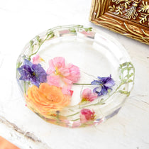 Flowers from wedding preserved in resin ring dish.